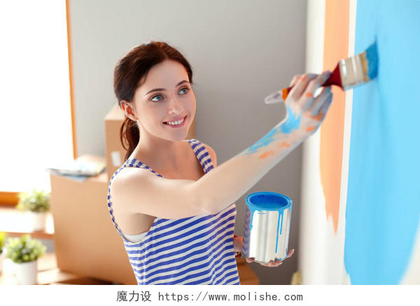 快乐微笑女人画室内墙上的新房子并幸福微笑的女人